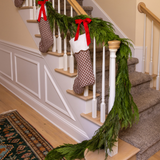 Decorative Christmas stockings hanging on a staircase with greenery.
