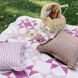 Trudie Constance Chocolate Ruffled Throw Pillow shown with pillows and quilt